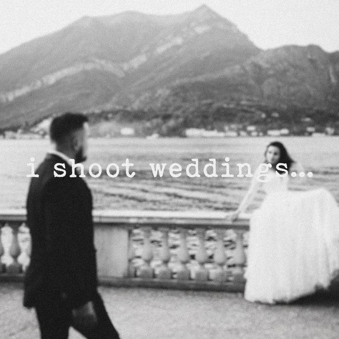 Crno-bijela fotografija: mladoženja u prvom planu i mladenka uz kamenu ogradu pokraj jezera i planina, s natpisom „i shoot weddings…”